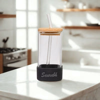 Clear glass drink container with wooden lid and straw on a kitchen counter, featuring the brand 'Sawab'.