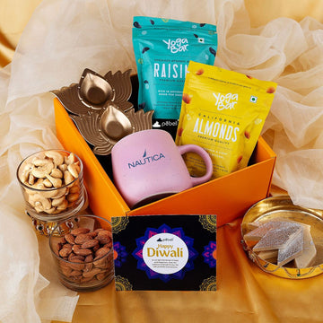 Gift basket with Nautica mug, 'Happy Diwali' card, and snacks on a yellow fabric background